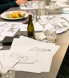 live nude drawings on table with food and drinks